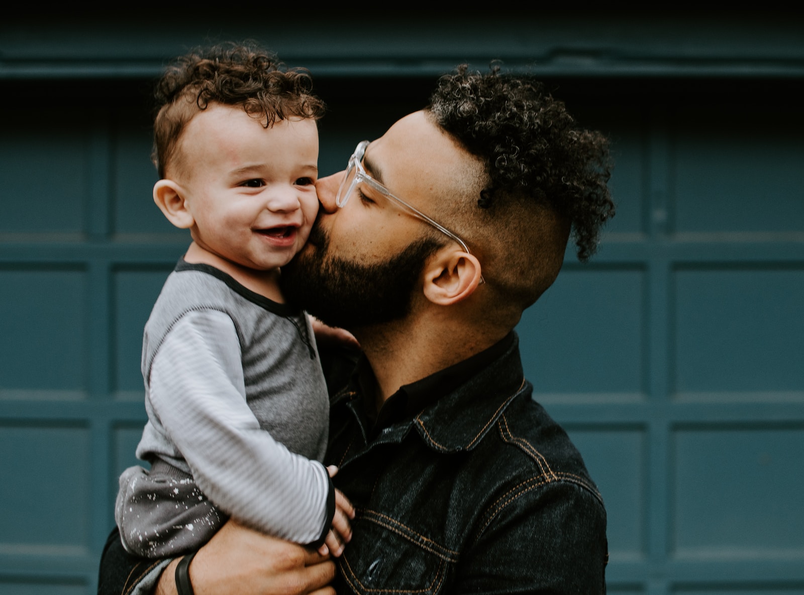 Photo by Kelly Sikkema man carrying baby boy and kissing on cheek